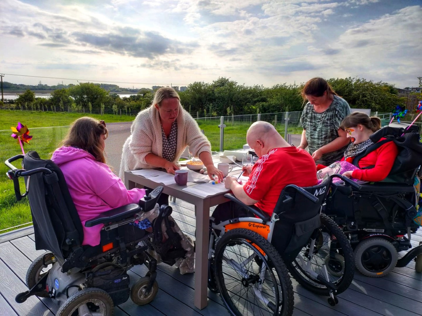 Guests sat on decking in wheelchairs enjoying a craft session